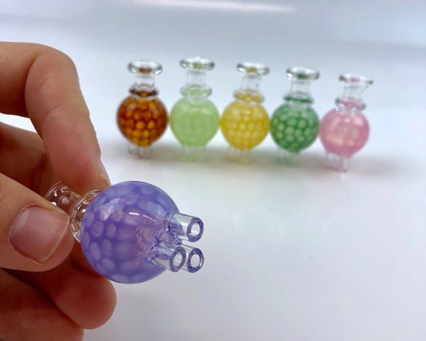 Hand Holding Alien Flower Monkey Triple Flow Bubble Cap Close Up with Other Assorted colours displayed in the back